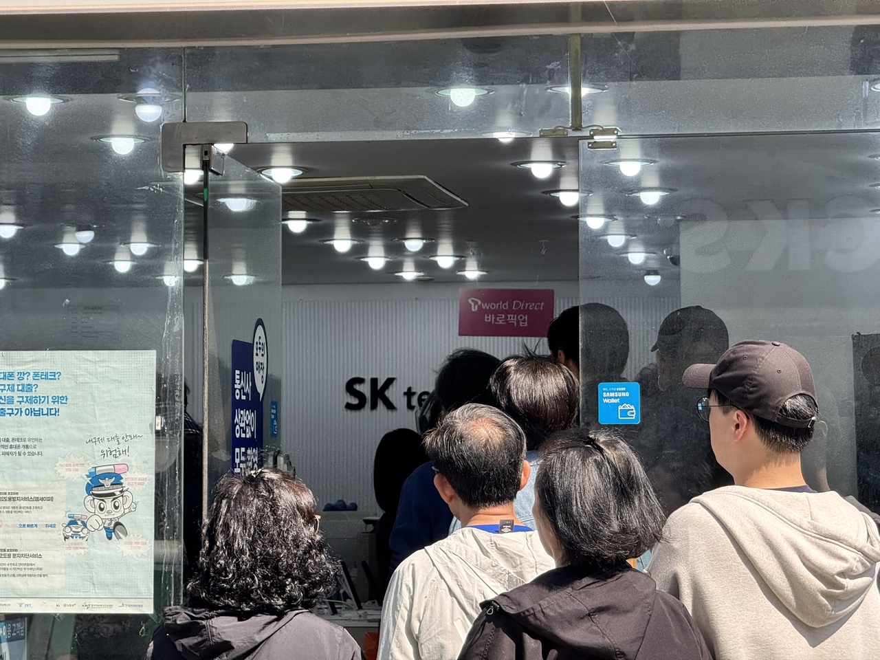 People gather at the doorway of SK Telecom’s Tworld Sookmyung Women’s University Entrance Branch in Seoul on Monday, seeking to book USIM card replacement appointments amid surging demand. (Moon Joon-hyun/The Korea Herald)