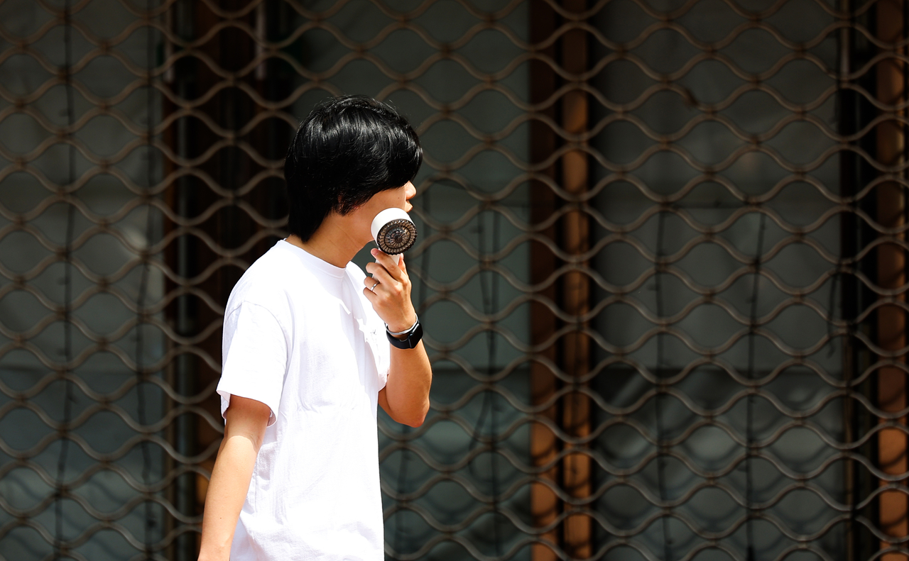 A pedestrian walks past with a portable fan in his hand as high temperatures reached 30 degrees Celsius in Daegu on April 18. (Yonhap)
